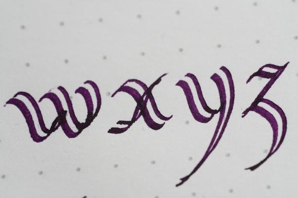 "wxyz" written in dark purple ink with dual line shadow effect nib