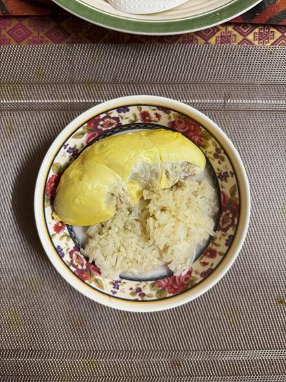 A bowl of Pulut soaked in Santan with a large piece of Durian on the side.