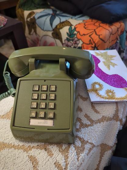 an olive green style western electric phone next to a hand made fathers day card.