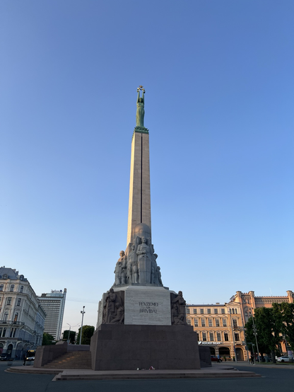 The Riga Freedom monument: A greenish statue of a woman holding up 3 stars, on top of a tall column