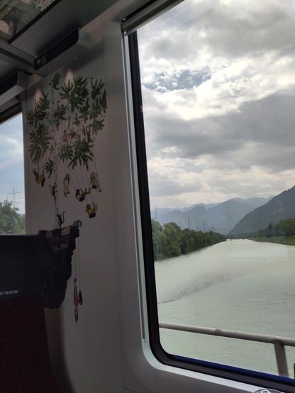 Foto. Eisenbahnwagen mit Illustrationen als Verzierung am Fensterrahmen und ein Fluss im Hintergrund.