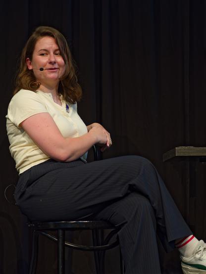 A photo of Cyd, sitting on a chair, answering some question and looking at the audience.