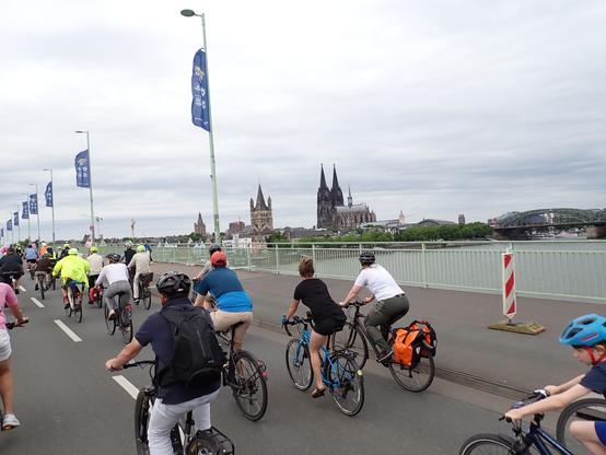 Radfahrende auf einer Brücke, Blick auf ein Stadtpanorama.