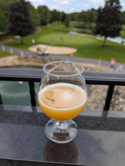 A hazy IPA overlooking the 18th green of a golf course.