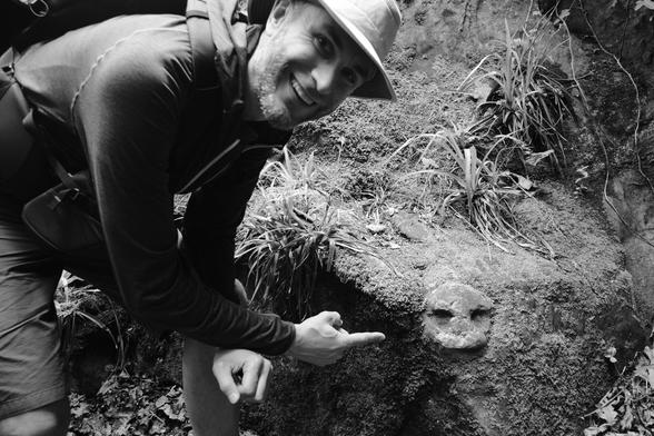 man pointing at a face carved into a rock. it's about the size of a dinner plate.