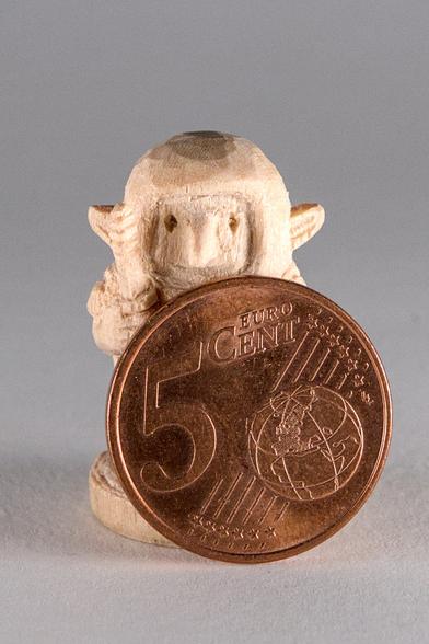 Frontansicht einer aus Holz geschnitzten Goblin-Miniatur, vor der eine 5-Cent-Münze steht.