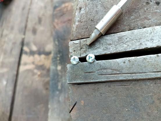 Two of the screws clamped into a vise next to each other. One had an angle grinder cut a slot down the length of the head. A matching slotted driver is next to it, which fits nicely now.