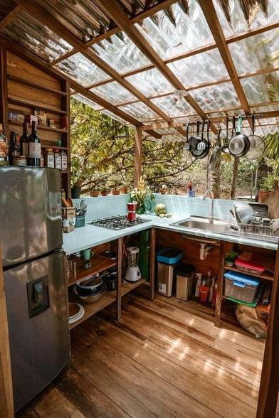 a rustic kitchen made of wood with clear plastic roof that has open sides.