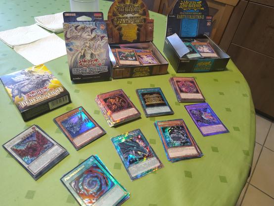 Diverse Stapel mit glitzernden Sammelkarten, ausgepackte Displays und Starterdecks.