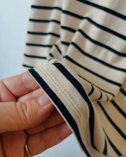 Closeup of triple-topstitched hem of bamboo tee in natural/black stripe colorway.