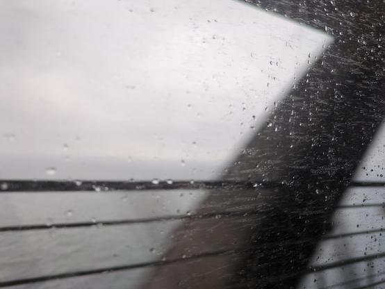 View out of an Øresundstog on Öresund Bridge

The picture is grey in grey and blurry. Parts of the bridge are out of focus as the train is passing.
It is a rainy day, there are rain drops on the window, some are in focus, others not. The water below is agitated and dark grey, the sky above cloudy and light grey.