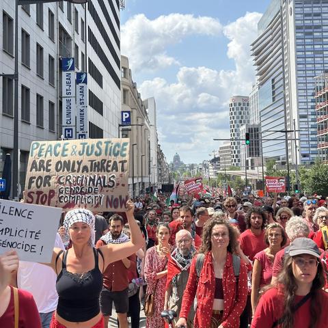 A similar picture as that upthread. Women in the foreground. One carries a sign saying “Peace and Justice are only a threat for criminals. stop genocide / complicity now” ; a French sign to the left repeats that second sentence.