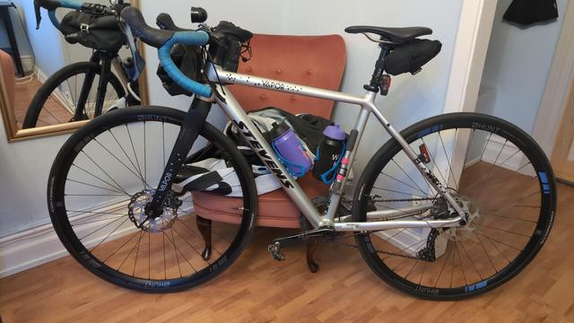 Ein silbernes Rennrad lehnt in einem Hotelzimmer an einem Sessel