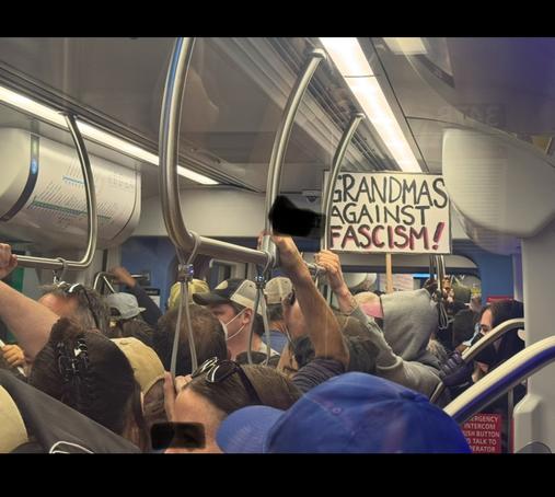 Packed Light-rail car and sign saying grandmas against fascism.