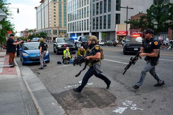 A man lays injured on the street as police respond to the shooting during the "No Kings" march in Salt Lake City Saturday.