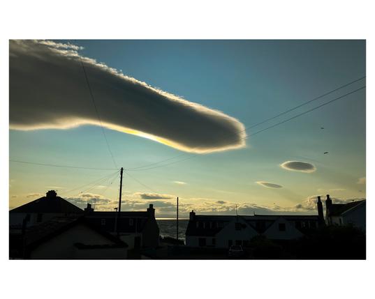 An unusual cloud formation over the rooftops of Portmahomack, that looks like a pointing finger with the sun behind it.