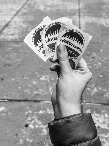 A hand holding three I voted early stickers
