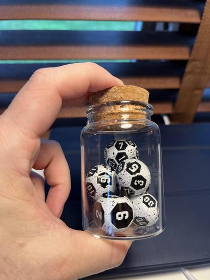 Photo of round-ish black and white soccer/football themed metal dice in a small jar.