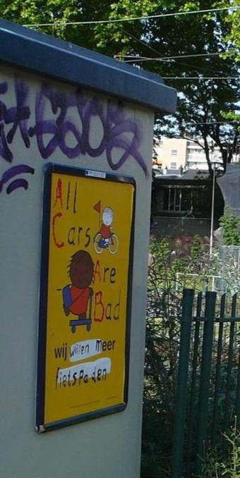 muur met blauwe rand bovenlangs en graffiti en geel reclamebord met wit Nijntje op fiets rechtsboven en bruin/zwart Nijntje op step midden voor
met tekst bijgeschreven: All Cars Are Bad
Wij willen meer fietspaden