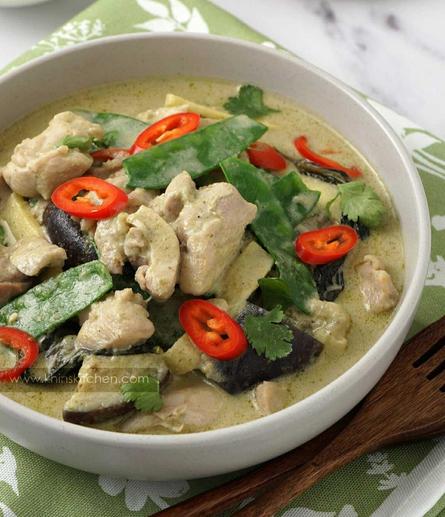 A plate of chicken and green mangetout, aubergine in a light green curry sauce