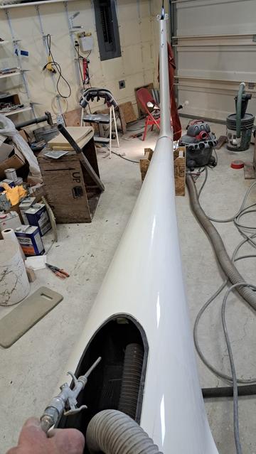 Looking at the tail boom from the forward end. The battery box door has been removed and a wide diameter, low pressure air hose has been inserted into the tail boom. I'm holding an air compressor hose fitting that blasts high pressure air...in order to loosen debris inside the tail boom. This, hopefully, will remove most of the debris from the tail boom.