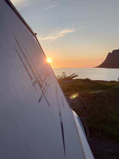 Die Sonne scheint zu Mitternacht über einem norwegischen Fjord und dem Meer