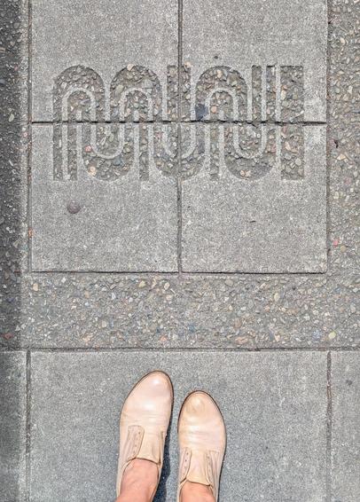 iconic SF MUNI logo embedded in the grey concrete paving 
shoes at the edge of the image