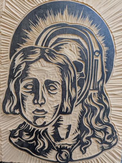 Portion of a linoleum block carved with a stylized depiction of the Mary Magdalene skull reliquary at Saint-Maximin-la-Sainte-Baume, France. It's a bust of woman with long hair, and the face opens to reveal the relic.