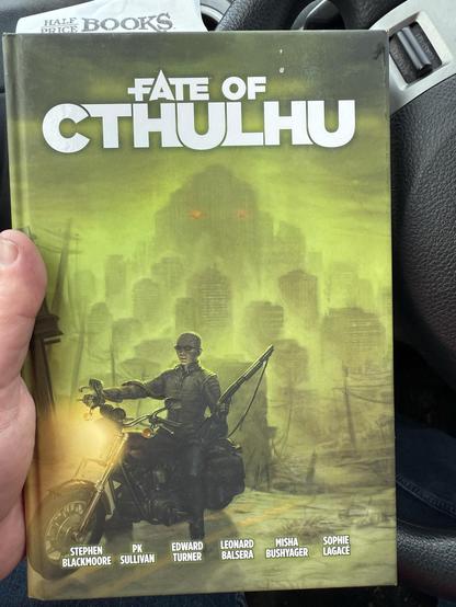 The image features the book "Fate of Cthulhu," showcasing its cover art. The cover depicts a figure on a motorcycle, holding a weapon, set against a backdrop of a desolate cityscape with a greenish hue.