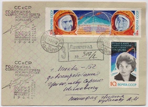 A vintage postcard featuring several Soviet space-themed stamps, including images of astronauts and spacecraft. The card is postmarked from Leningrad and contains handwritten text in Russian, detailing an address and notes related to space exploration events in 1964.