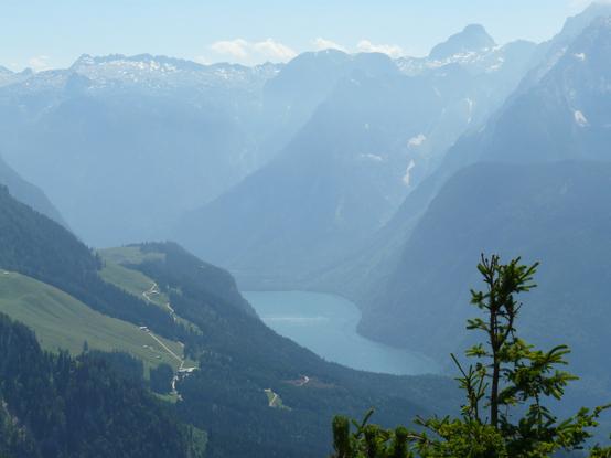 Tief liegender Königssee umgeben von hohen Bergen,
Morgendunst, blauer Himmel mit wenigen weißen Wolken