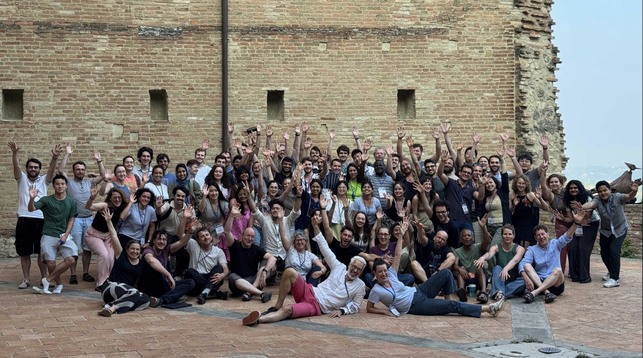 group picture: 60 students, 5 assistant tutors, 11 tutors, 2 keynoters and 2 directors, lined up and cheering to the camera!