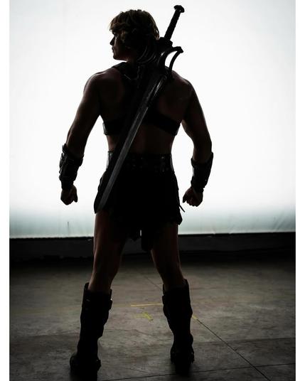 Foto dell'attore Nicholas Galitzine in penombra, dove si distinguono alcuni elementi tipici del costume di He-Man, come la spada e gli stivali