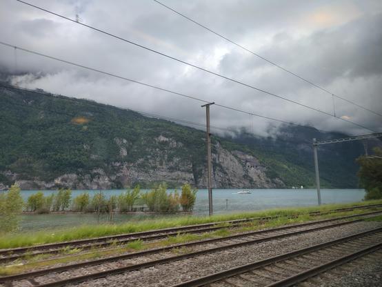 View out of a Railjet train along Walensee in Switzerland

Low hanging clouds are covering most of the mountain range Churfirsten. The wind is causing ripples on the lake surface. A medium size passenger ship is on the lake.