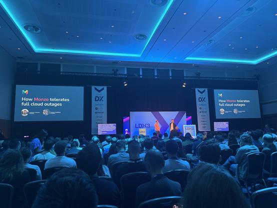 andrew lawson and daniel chatfield on stage at lead dev, talking about how monzo tolerates full cloud outages to a full room