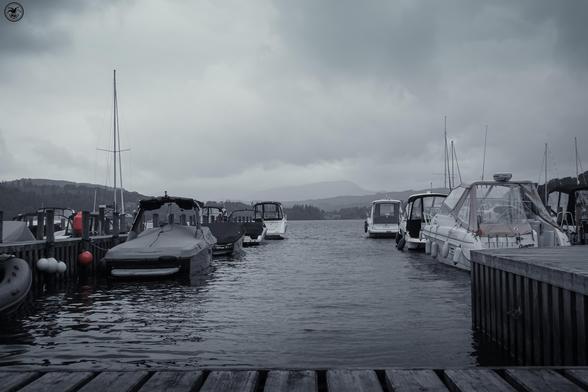 Monochrome shot of small boats at wooden jetty on lake water