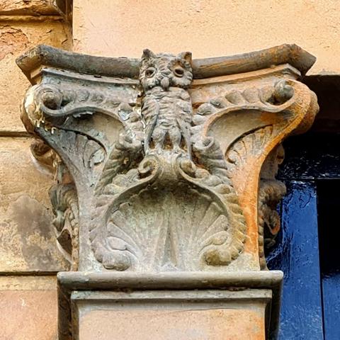 A small sculpted owl on an ornate column capital.