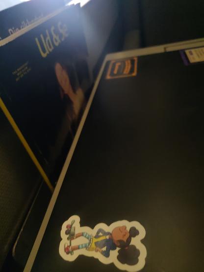 Billede af Ada sticker på en laptop der ligger foran et ud&se magasin der stikker op fra sin lomme under DSB togets vindue.