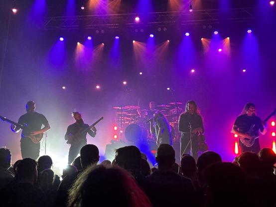 Ne Obliviscaris on stage, with five performers lined across the front of the stage. Photo taken over the heads of the audience.