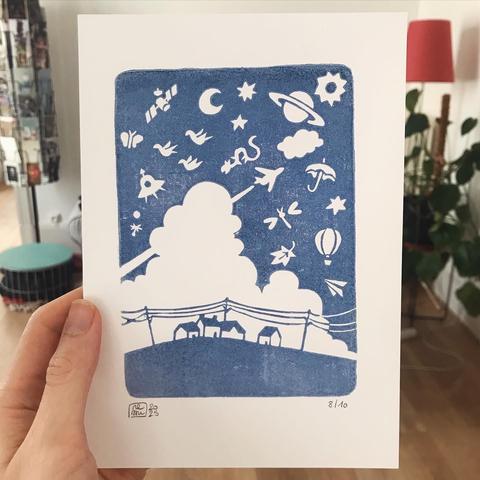 Linocut picture printed in blue ink. A few houses and power lines under a blue sky filled with flying objects: a huge cloud, a satellite, planets, sun and moon, a plane, a hot air balloon, a dragon, a UFO, a leaf, insects and birds.