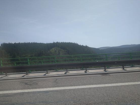Blick aus dem Autofenster auf den Rand der Talbrücke und bewaldete Hügel