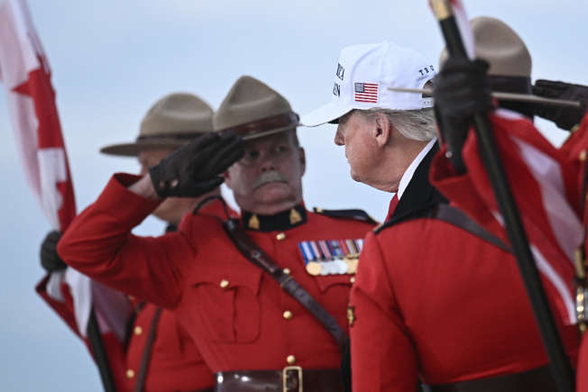 A Canadian officer salutes Donald Trump but he is leaning as far back as he can and he has a look of disgust mixed with dislike on his face.