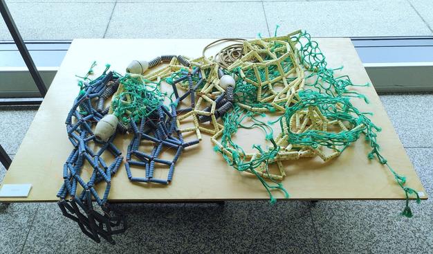 Ceramic floaters, lines and ceramic fishing net combine with real fishing net parts displayed on a table.