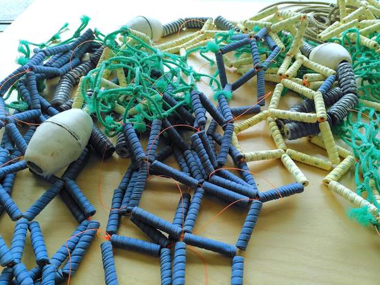 Ceramic floaters, lines and ceramic fishing net combine with real fishing net parts displayed on a table.