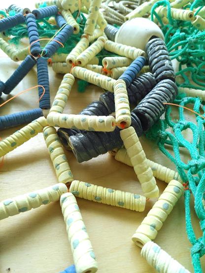Ceramic floaters, lines and ceramic fishing net combine with real fishing net parts displayed on a table.