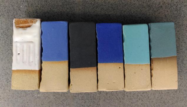 A series of 6 glaze test tiles aligned. From left to right: white matte glaze, royal blue matte, black matte, navy bleu matte, turquoise matte, green matte.