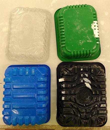 4 plastic containers one transparent, one green, one blue and one black.