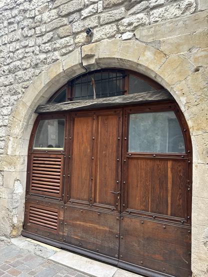 Wooden door within stone arch. Bundle of wheat above the door.
