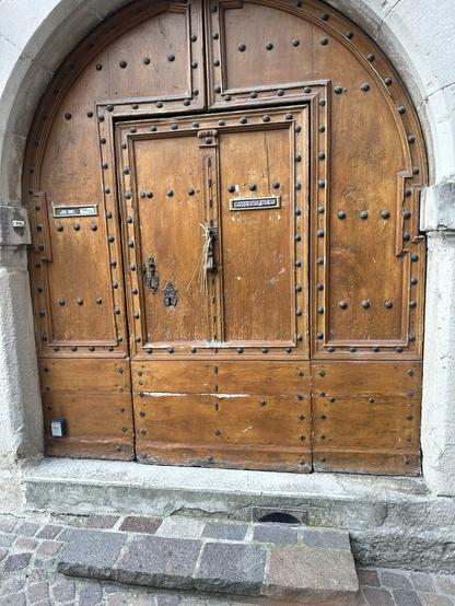 Wooden door within stone arch. Bundle of wheat attached to the handle.