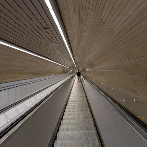 Very long escalator tunnel creating a vanishing point effect.